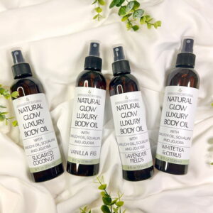 Set of 4 body Oils laying on a draped white cloth